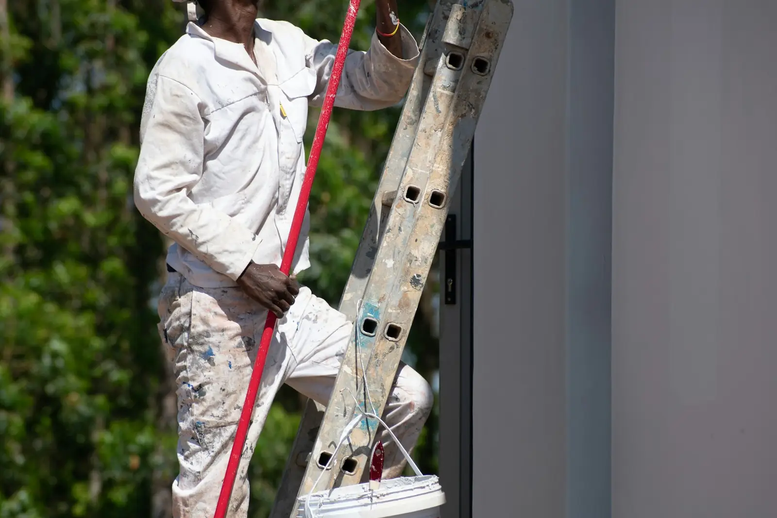 Painter and decorator on a ladder with a tin of paint
